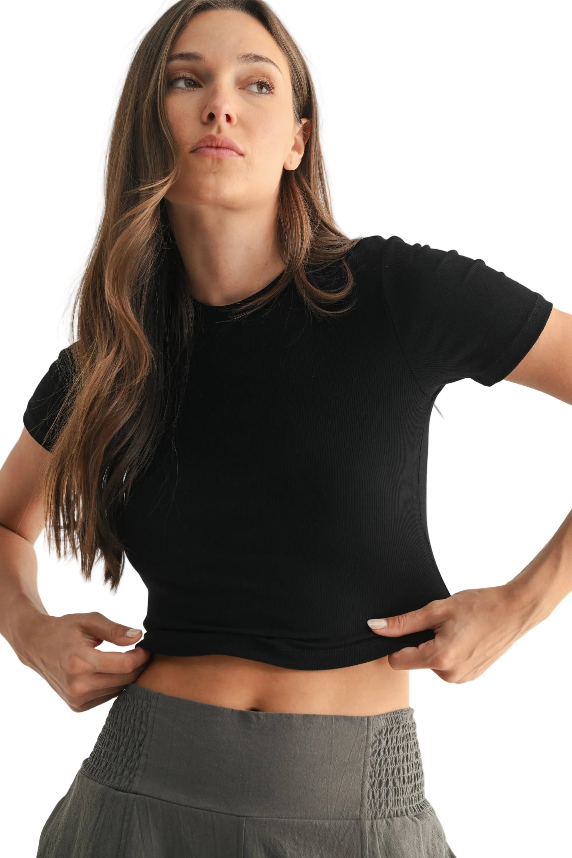 Woman wearing a black crop top and gray skirt against a white background