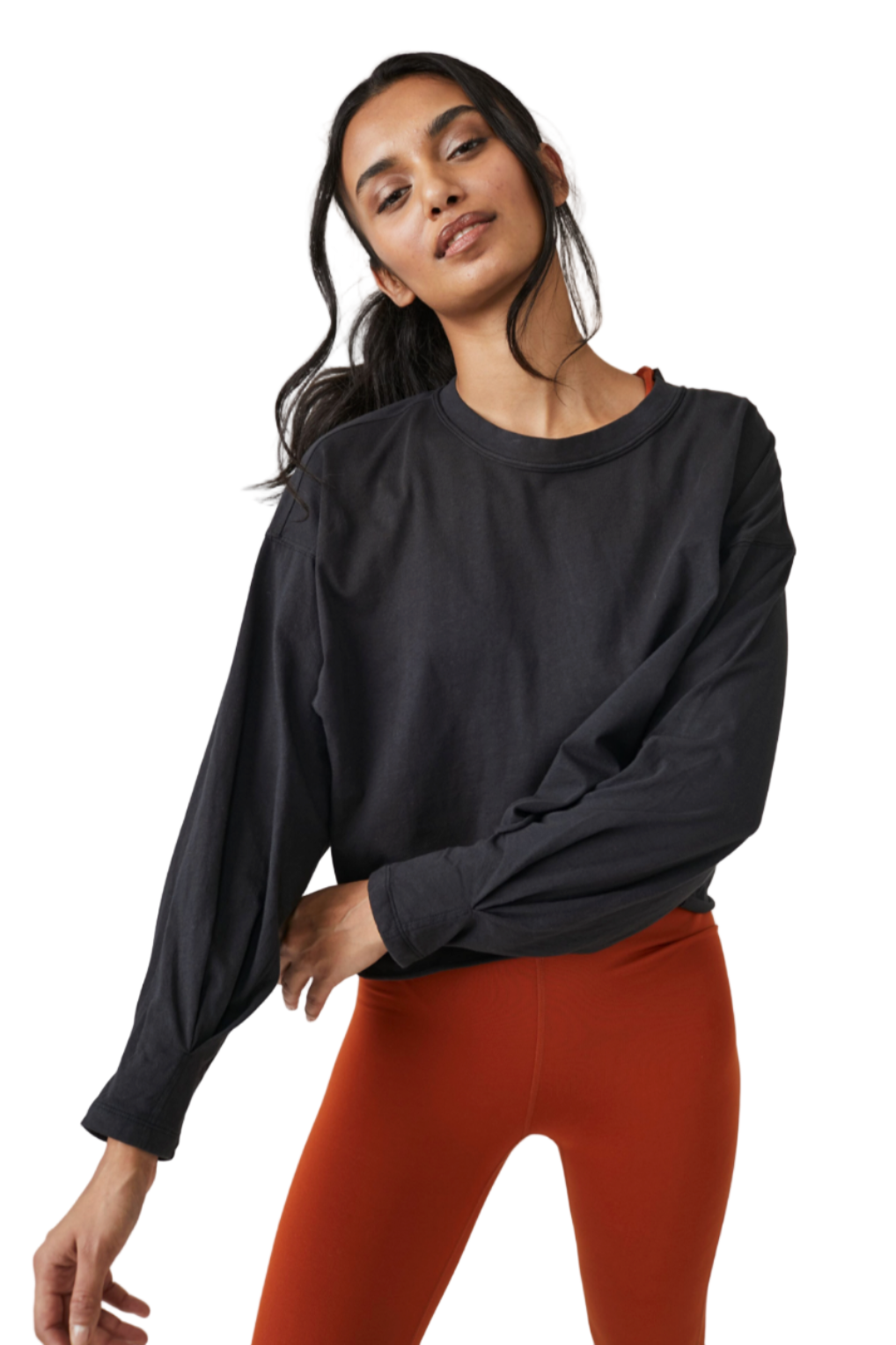 Woman wearing a black long-sleeve top and red leggings on a light gray background