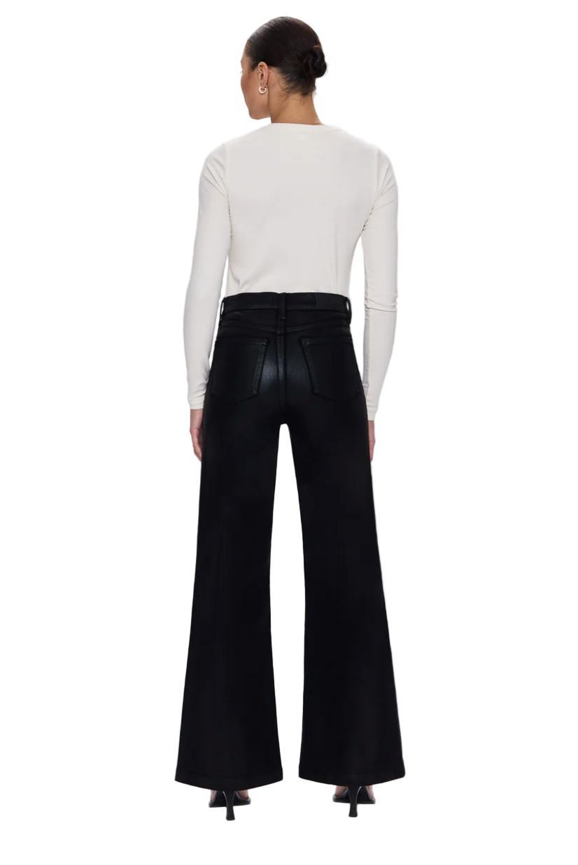 Person wearing black wide-leg jeans and a white top on a light gray background