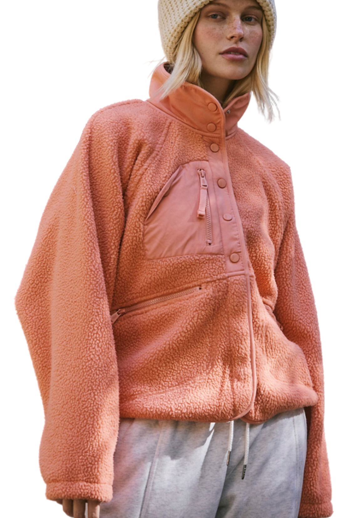 Person wearing a pink fleece jacket and beige beanie in an outdoor setting