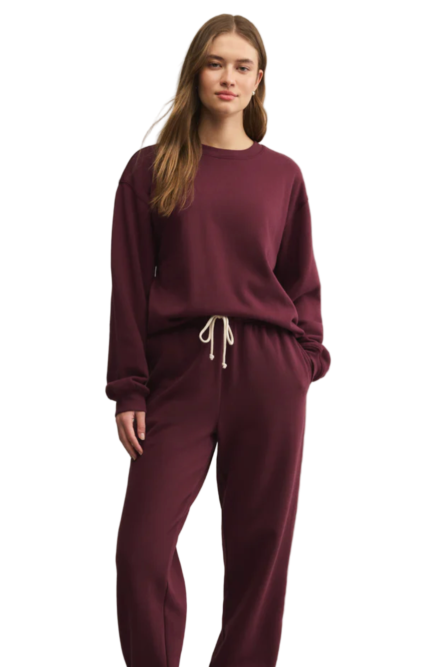 Woman wearing a burgundy loungewear set on a beige background