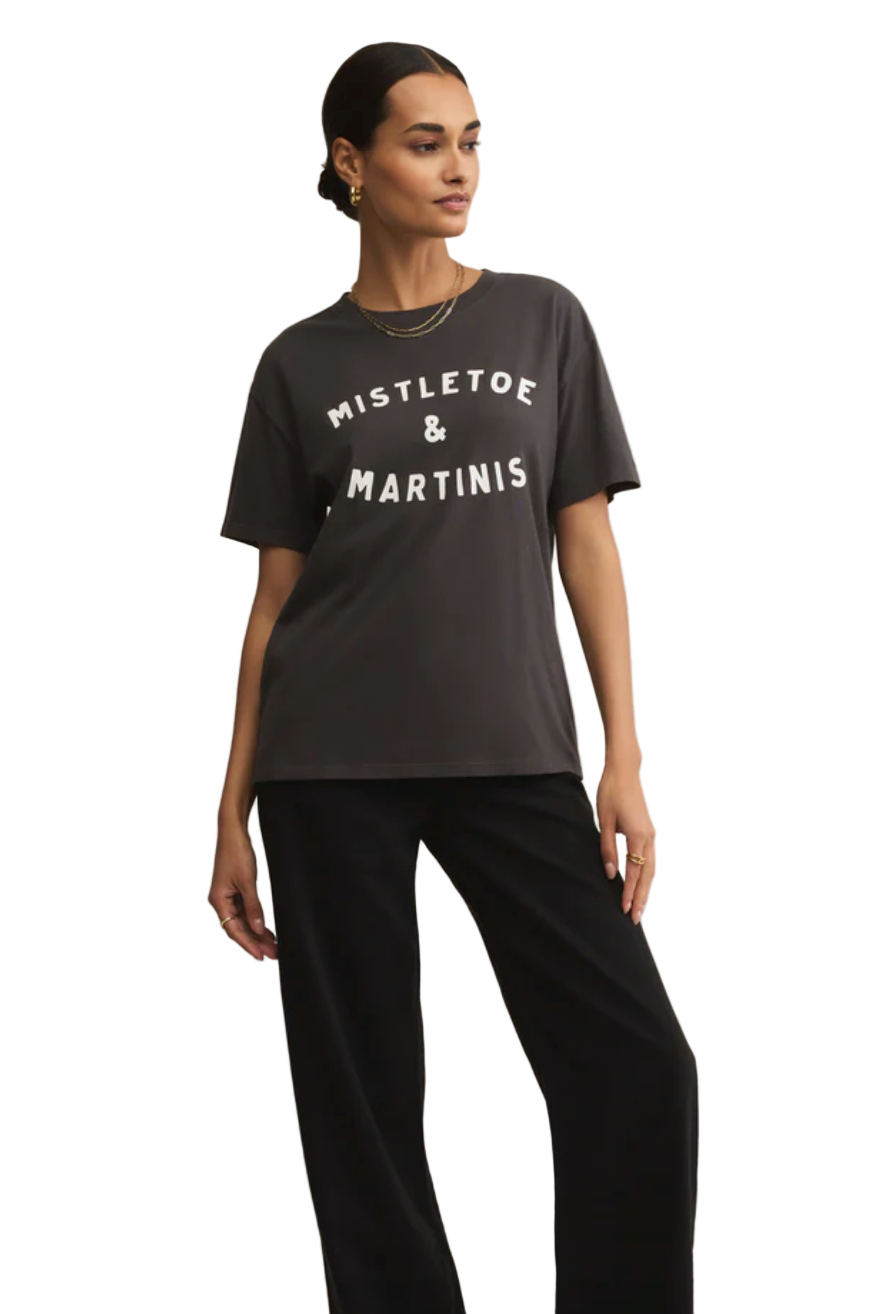Woman wearing a black t-shirt with 'MISTLETOE & MARTINIS' text on a beige background