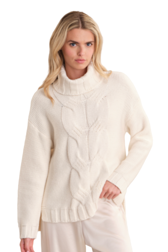 Woman wearing a white cable knit sweater against a plain background