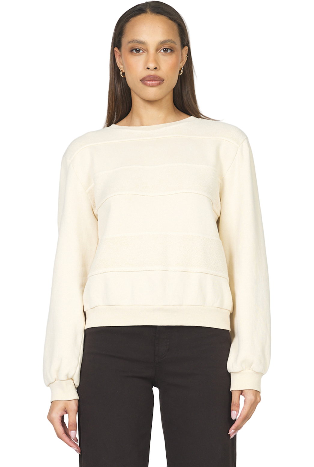 Woman wearing a cream sweater and black pants on a white background