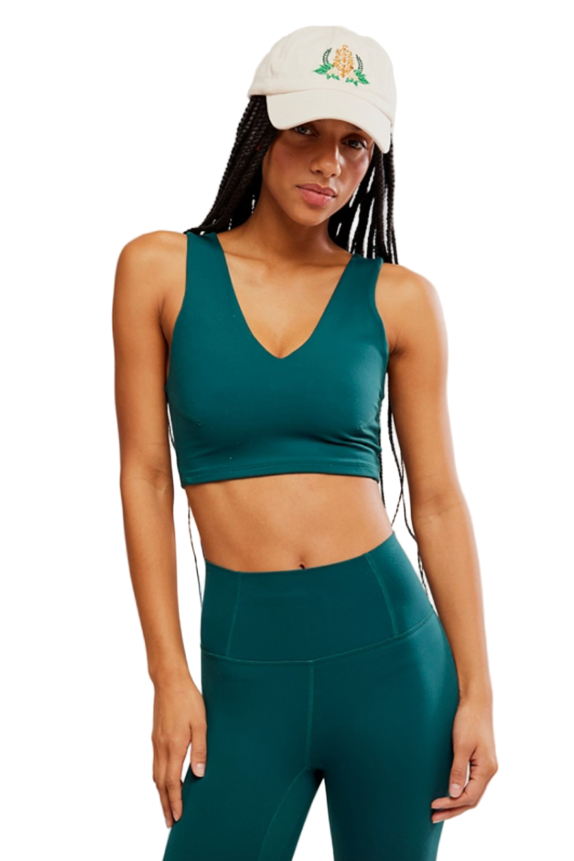 Woman wearing a green sports bra and leggings set with a white cap on a light gray background