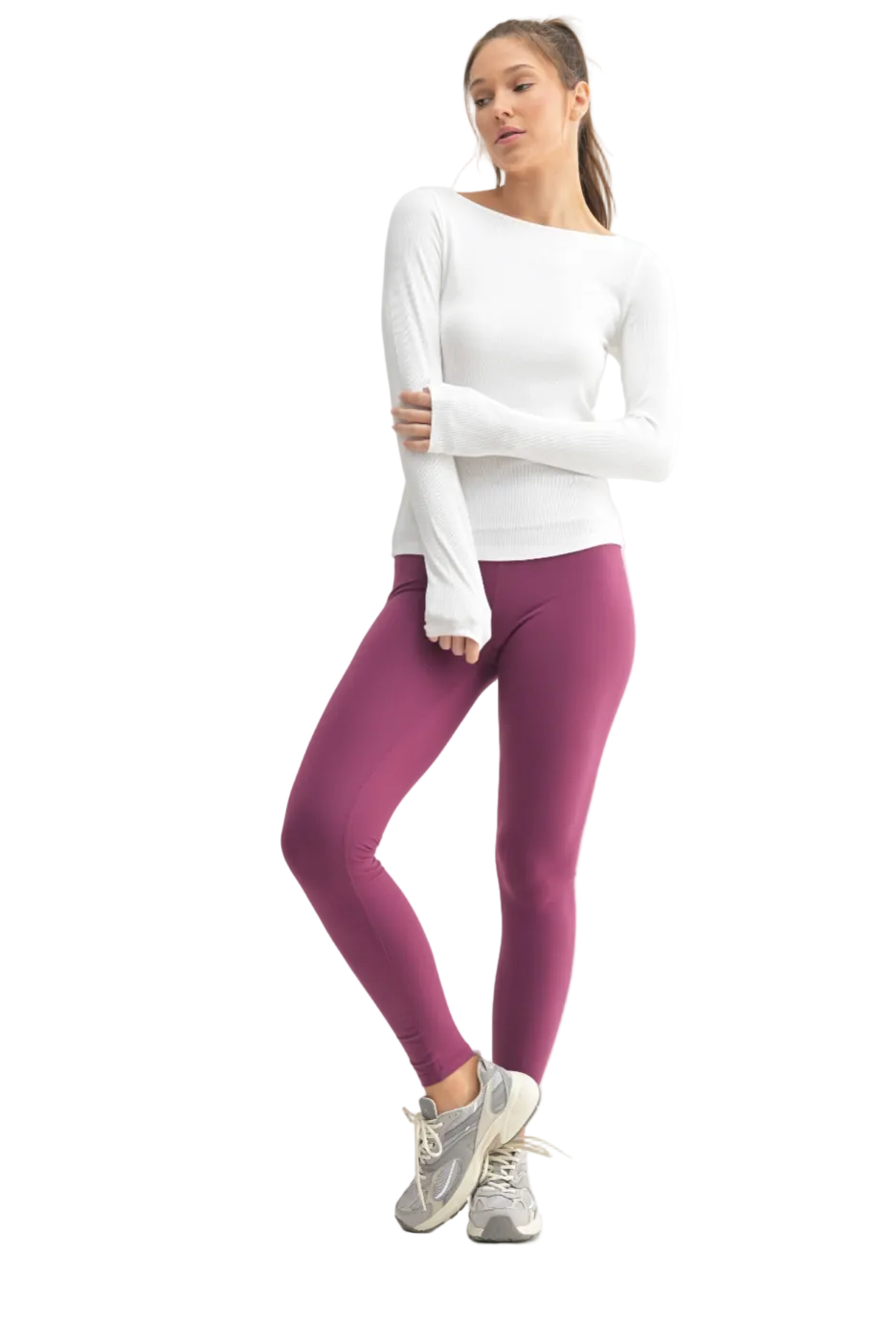 Woman wearing a white long-sleeve top and purple leggings on a white background