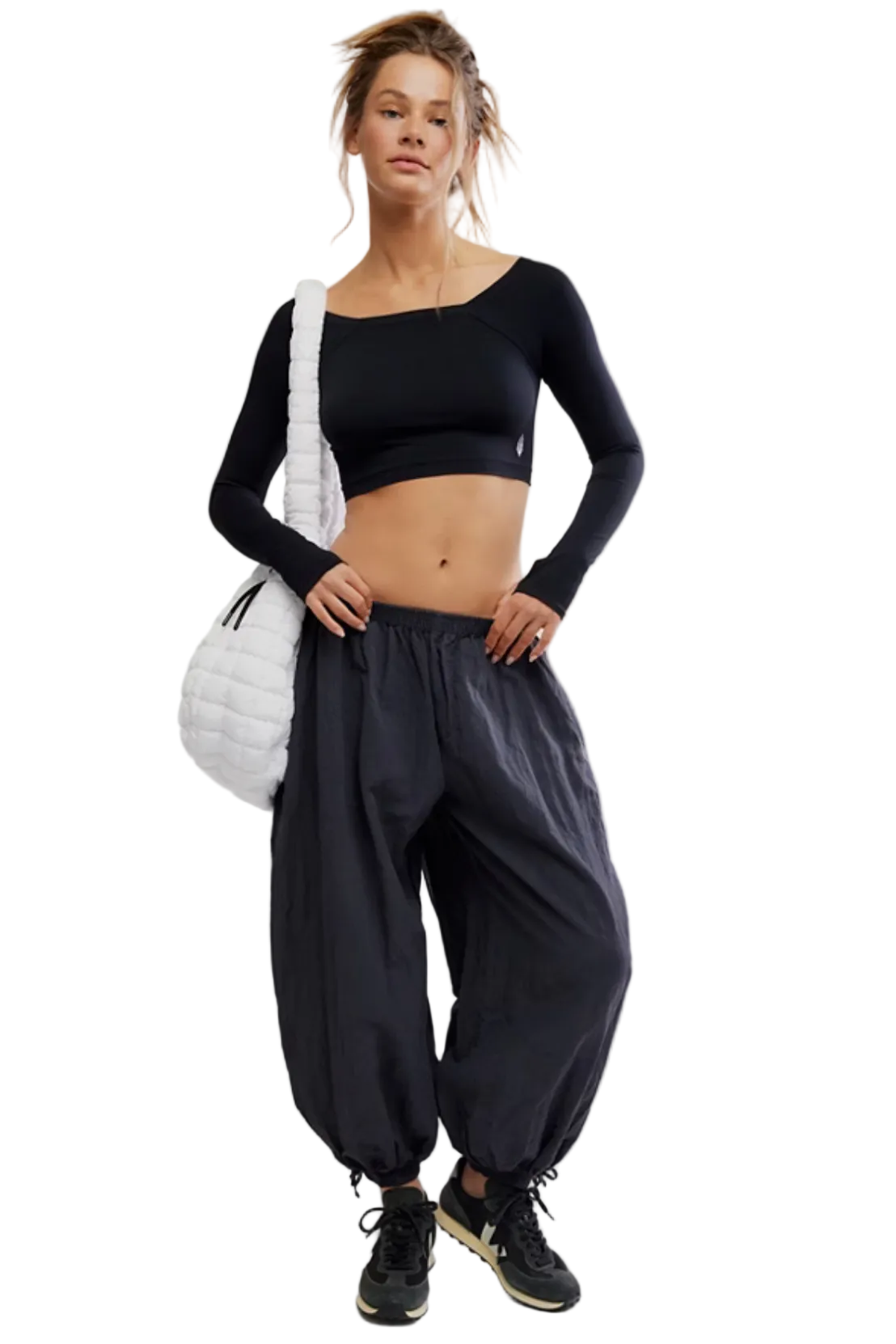 Woman wearing a black long-sleeve crop top and wide-leg pants on a white background