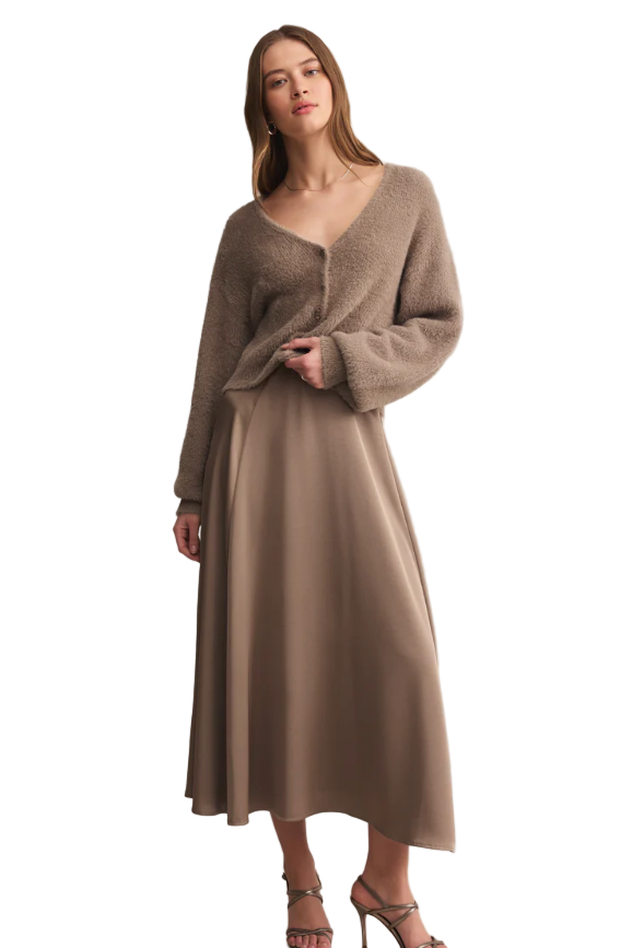 Woman wearing a brown dress and cardigan against a beige background