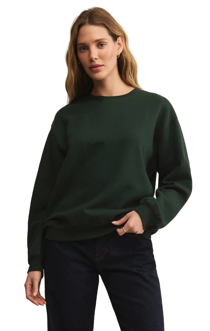 Woman wearing a dark green sweater against a beige background