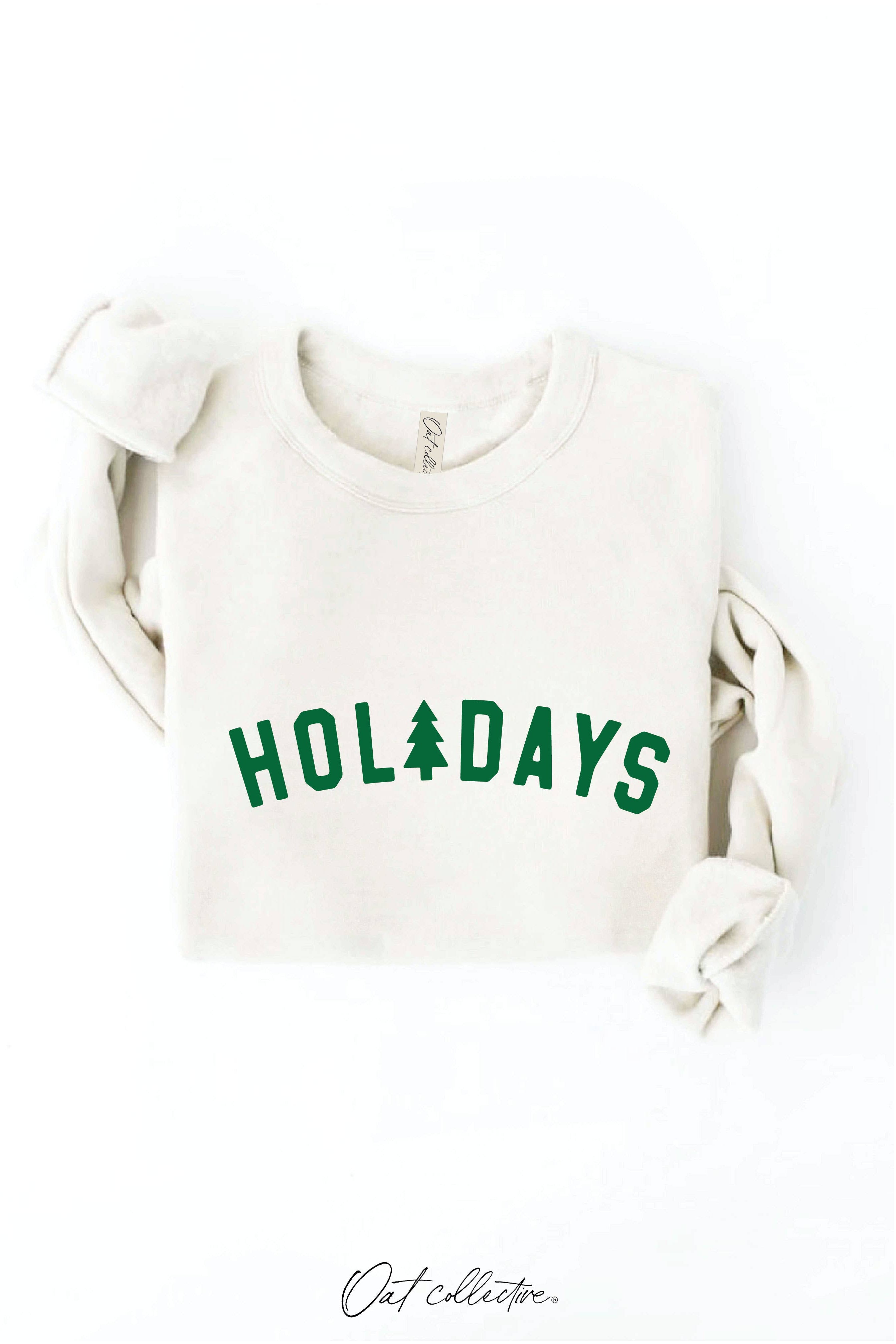Oat Collective white sweatshirt with 'HOLIDAYS' text and green trees on a white background