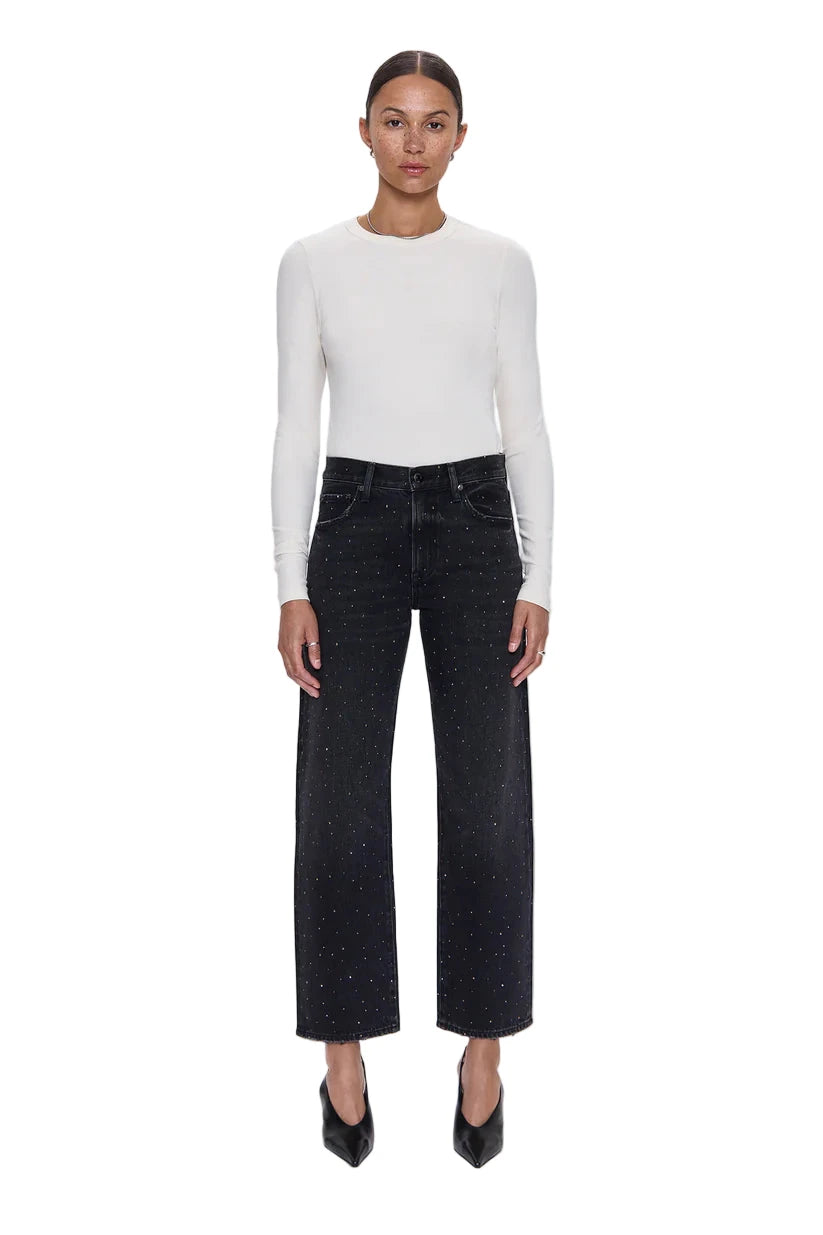 Woman wearing a white long-sleeve top and black pants on a white background