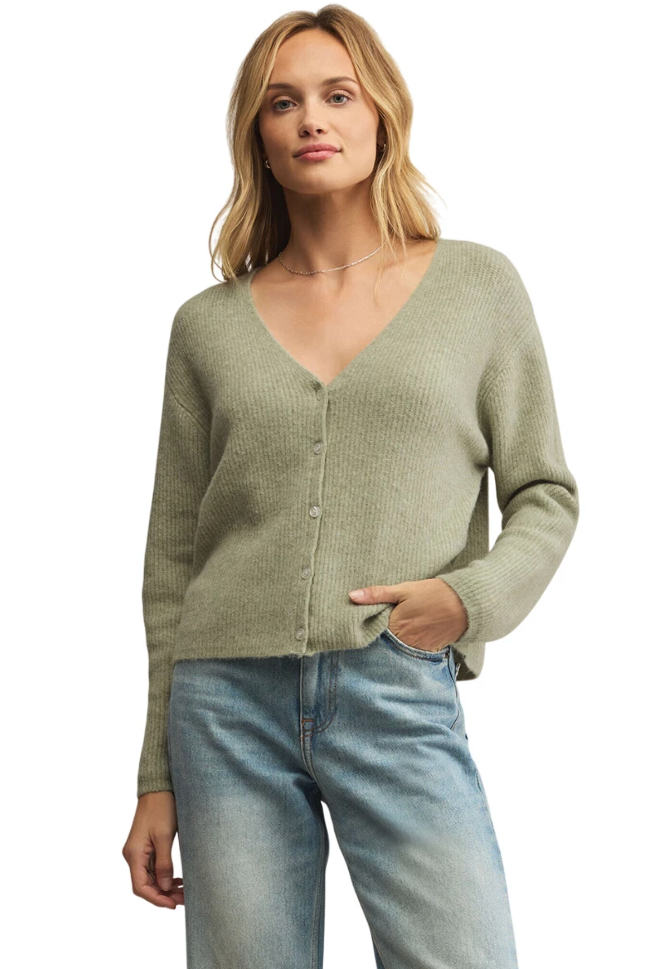 Woman wearing a green sweater and blue jeans on a white background