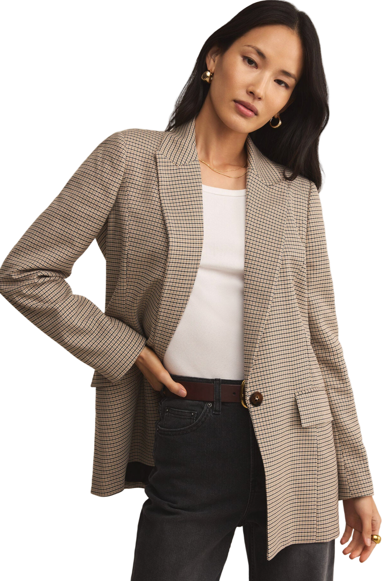 Woman wearing a checkered blazer over a white top and black pants on a beige background