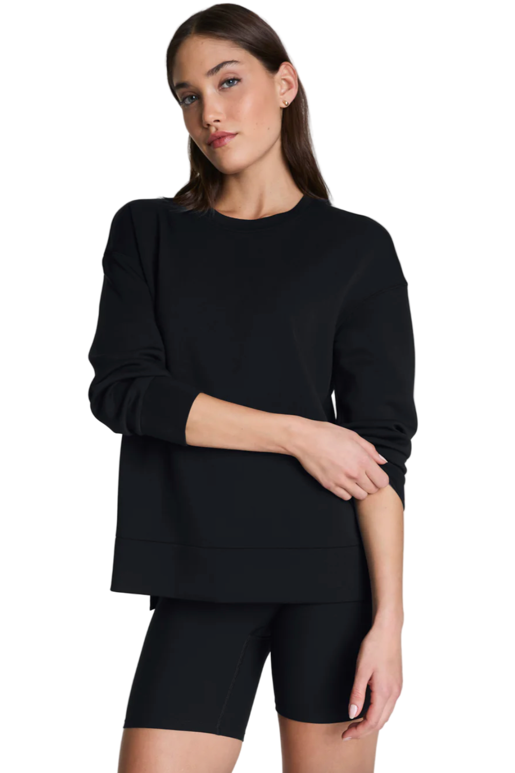Woman wearing a black sweatshirt and black shorts on a light gray background