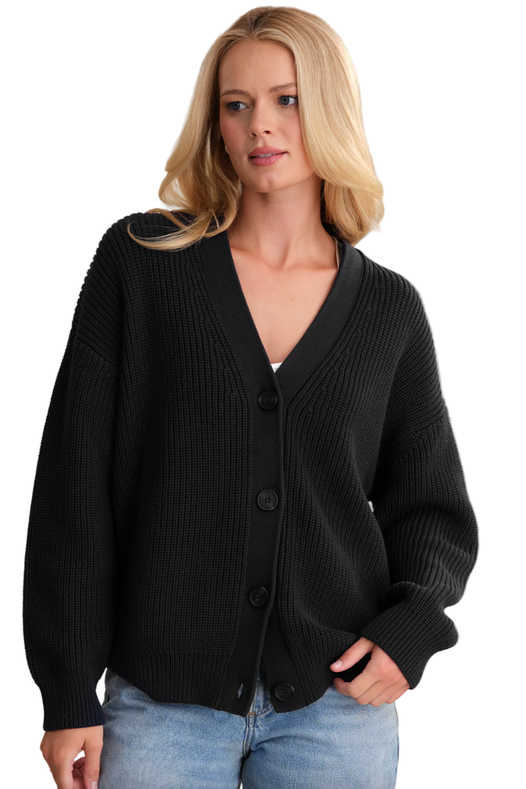 Woman wearing a black cardigan over a white shirt with blue jeans on a beige background
