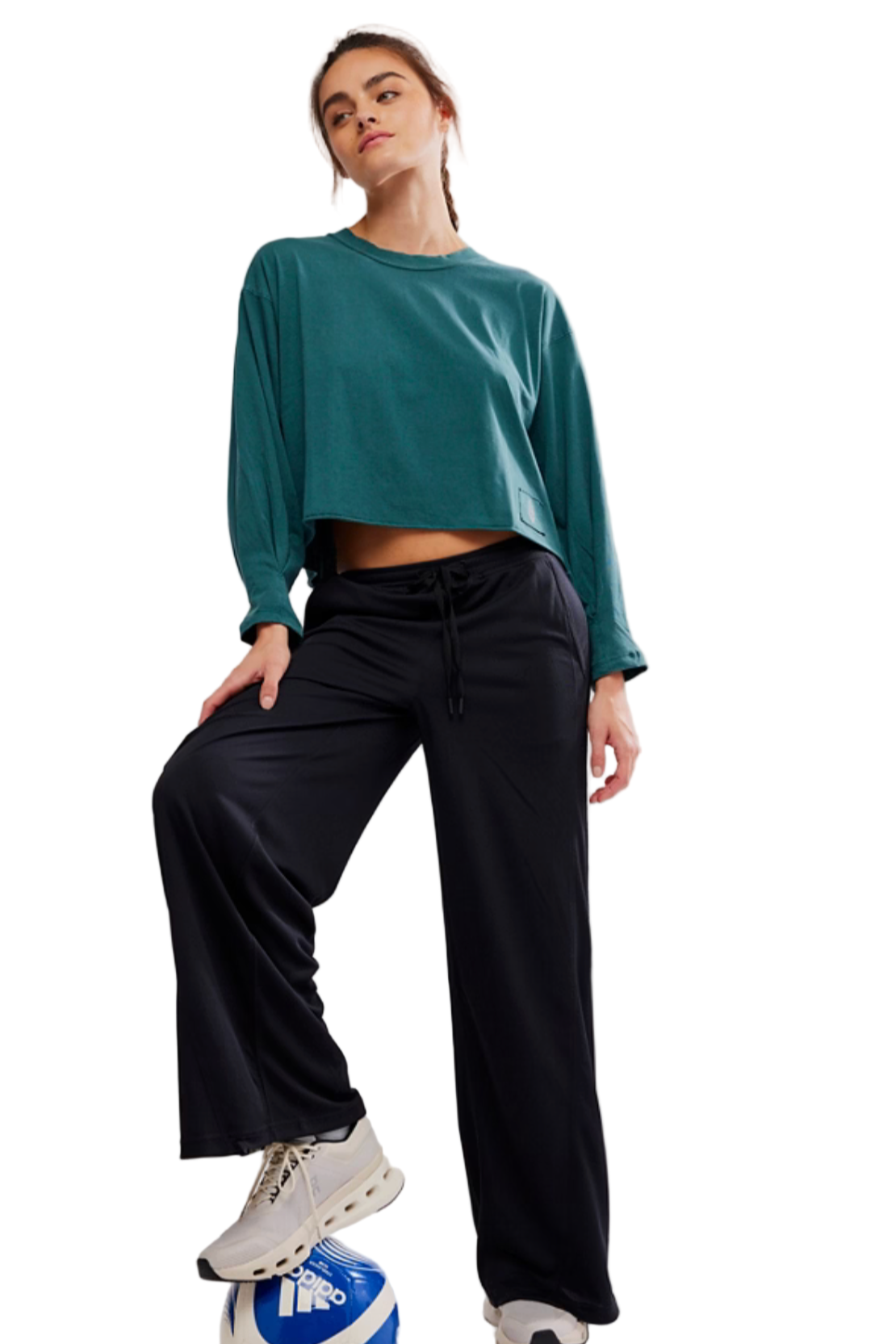 Person wearing a teal long-sleeve top and black pants on a white background