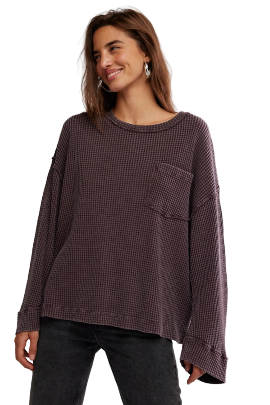 Woman wearing a brown checkered sweater with a pocket on a plain background