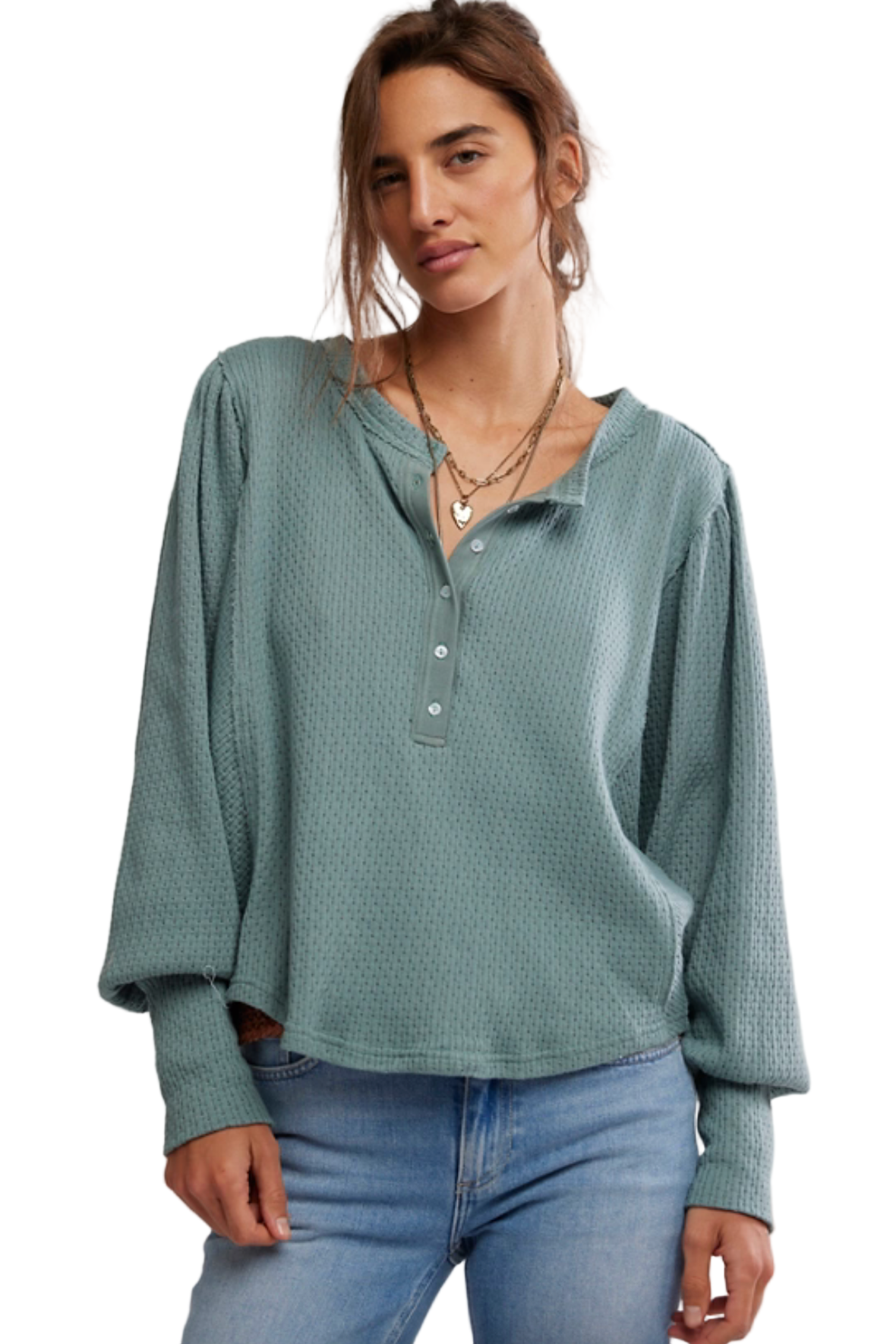 Woman wearing a textured green long-sleeve top and blue jeans against a plain background