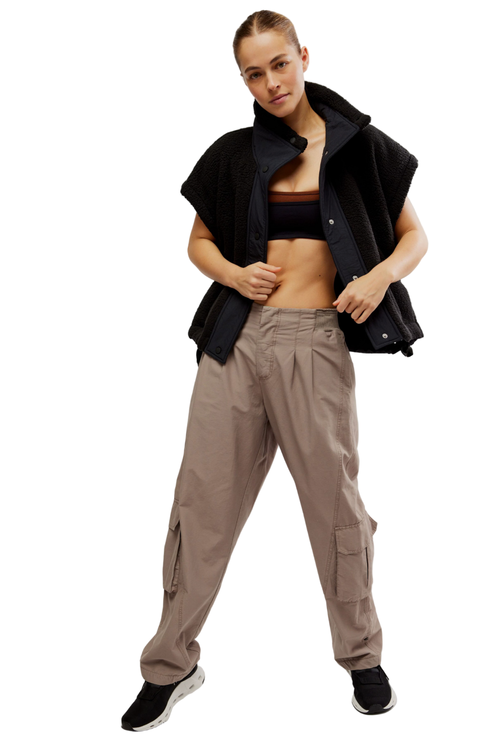 Person wearing a black sleeveless jacket, brown pants, and black shoes on a white background