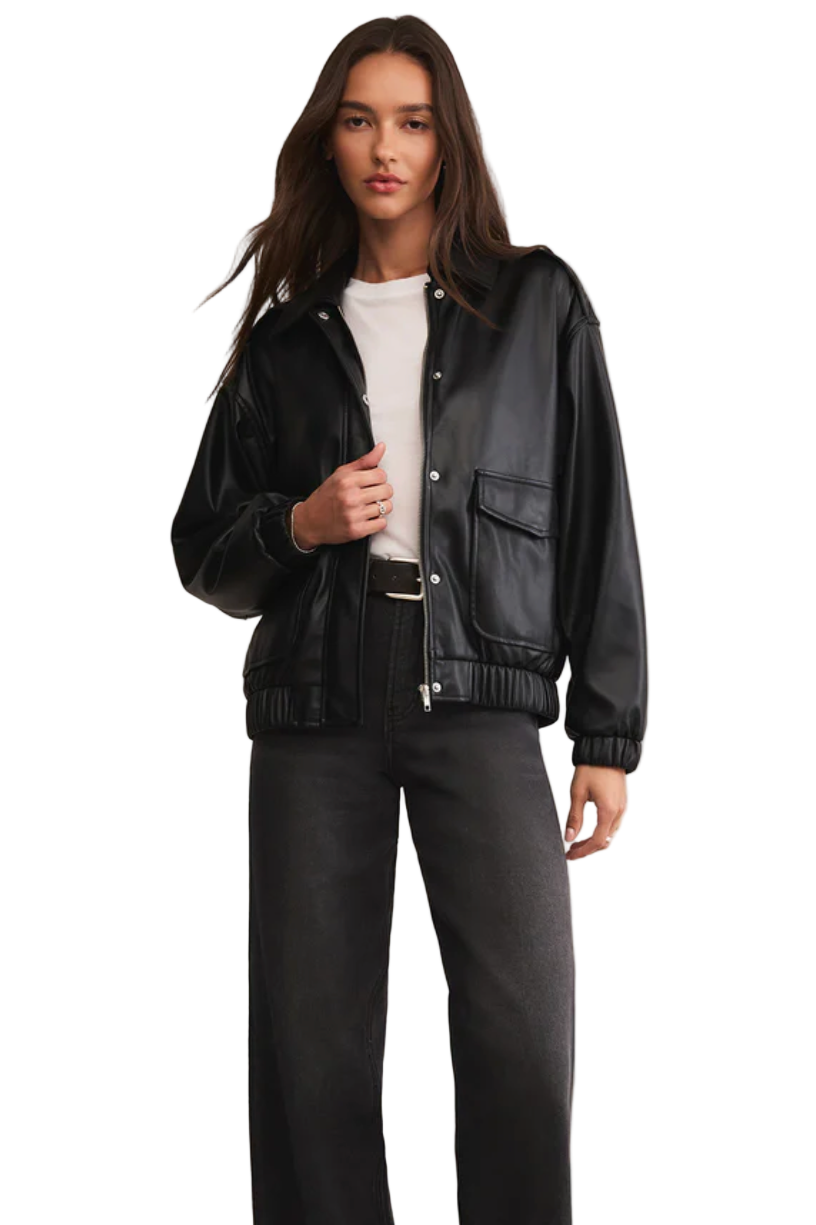 Woman wearing a black leather jacket and pants on a beige background