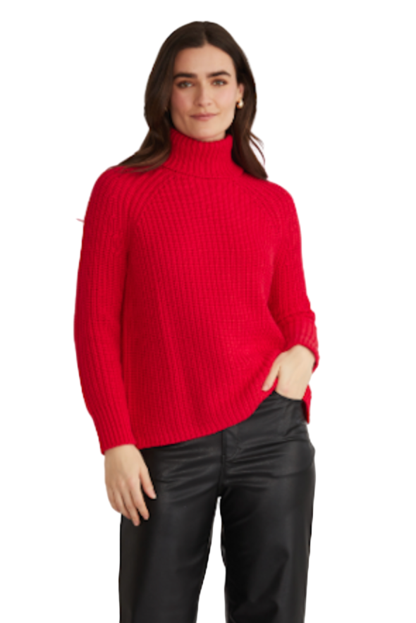 Woman wearing a red turtleneck sweater and black pants on a light gray background