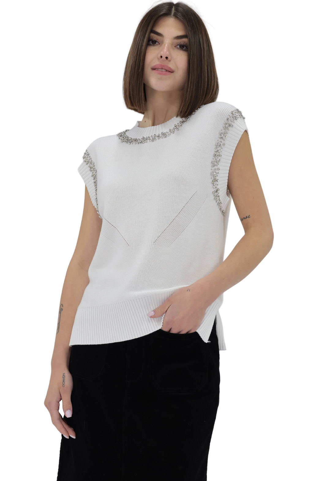Woman wearing a white sleeveless top with embellishments on a plain background