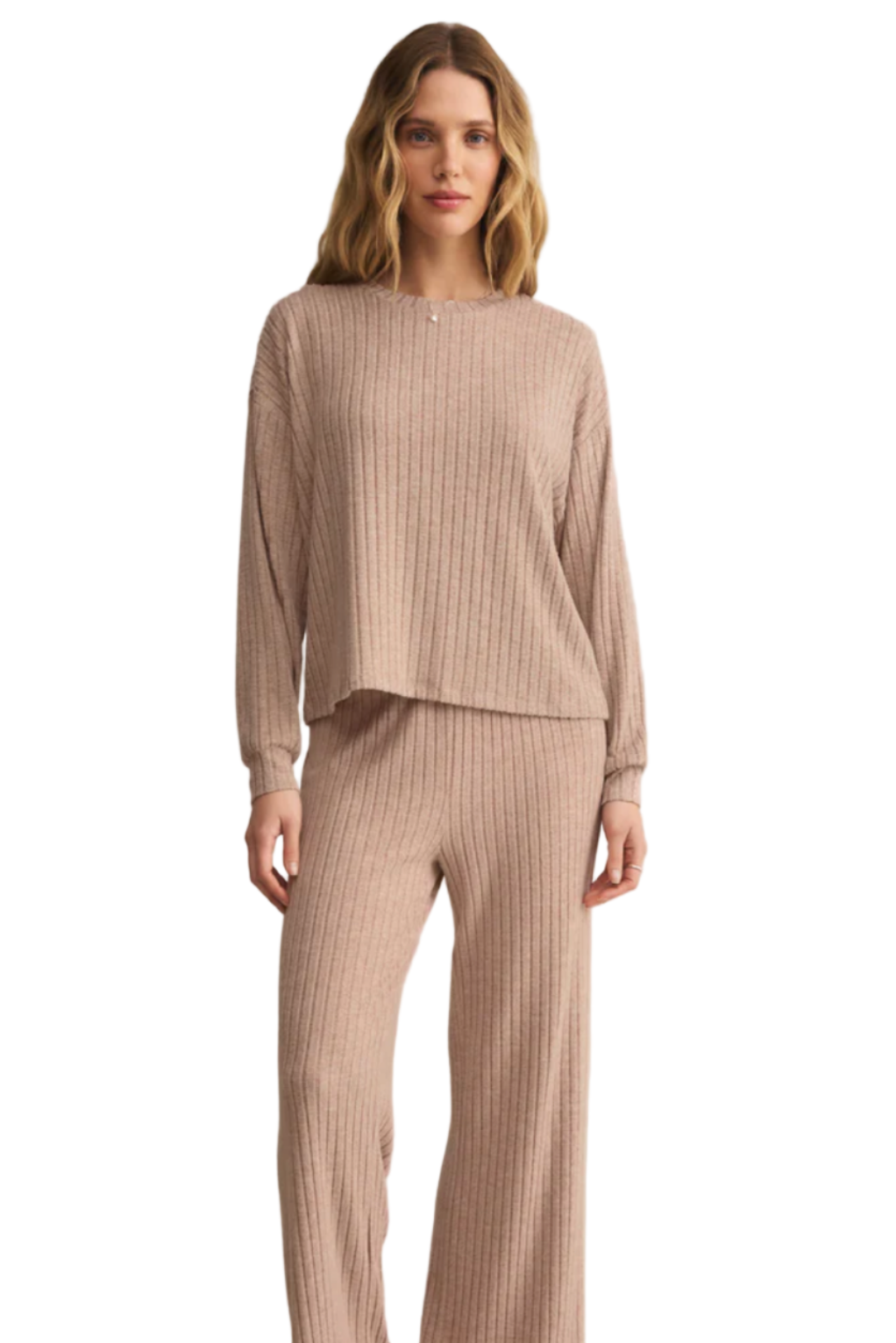 Woman wearing a beige ribbed top and pants on a light pink background