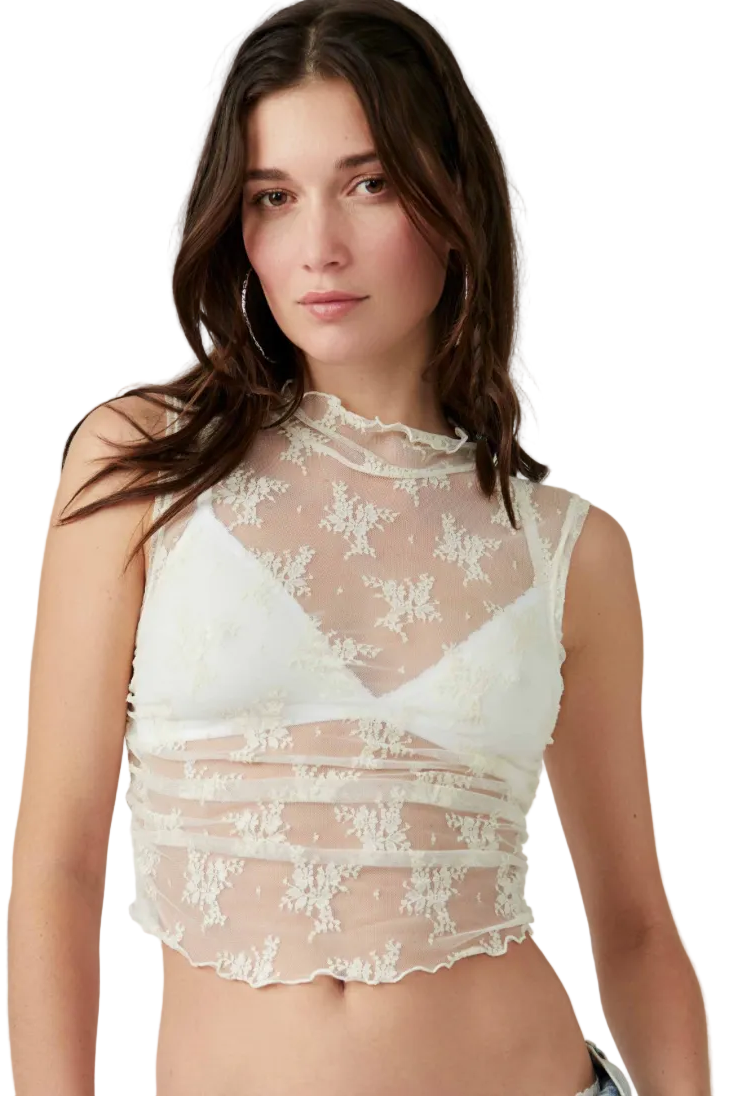 Woman wearing a white lace top against a plain background