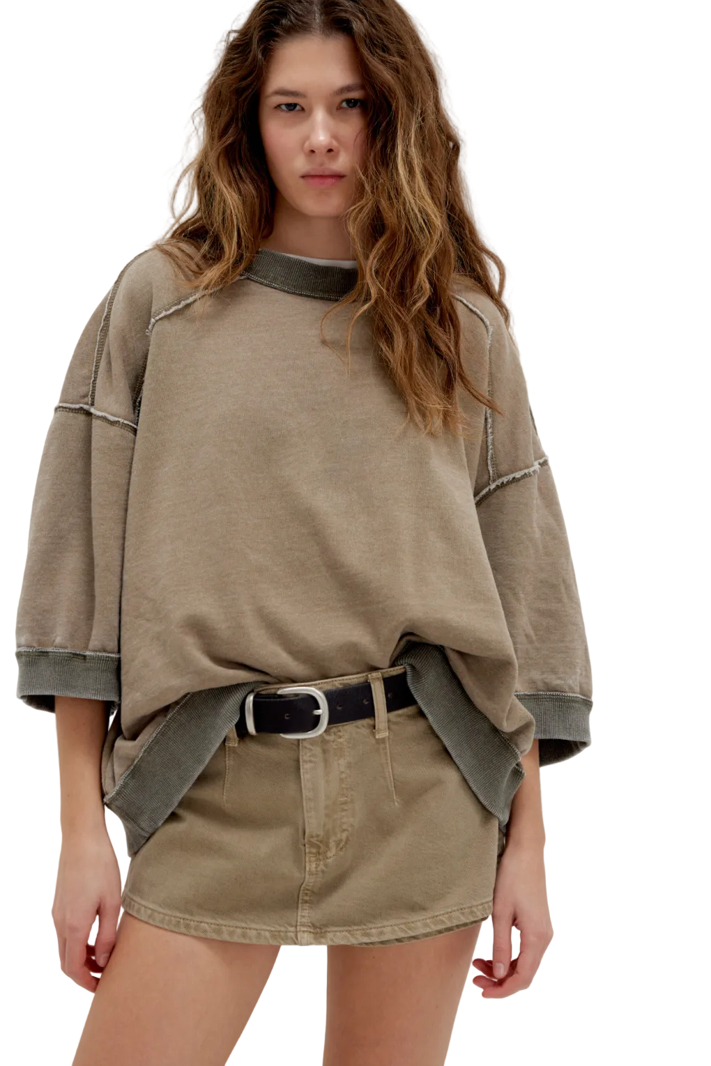 Woman wearing a beige oversized sweater and skirt with a belt on a white background