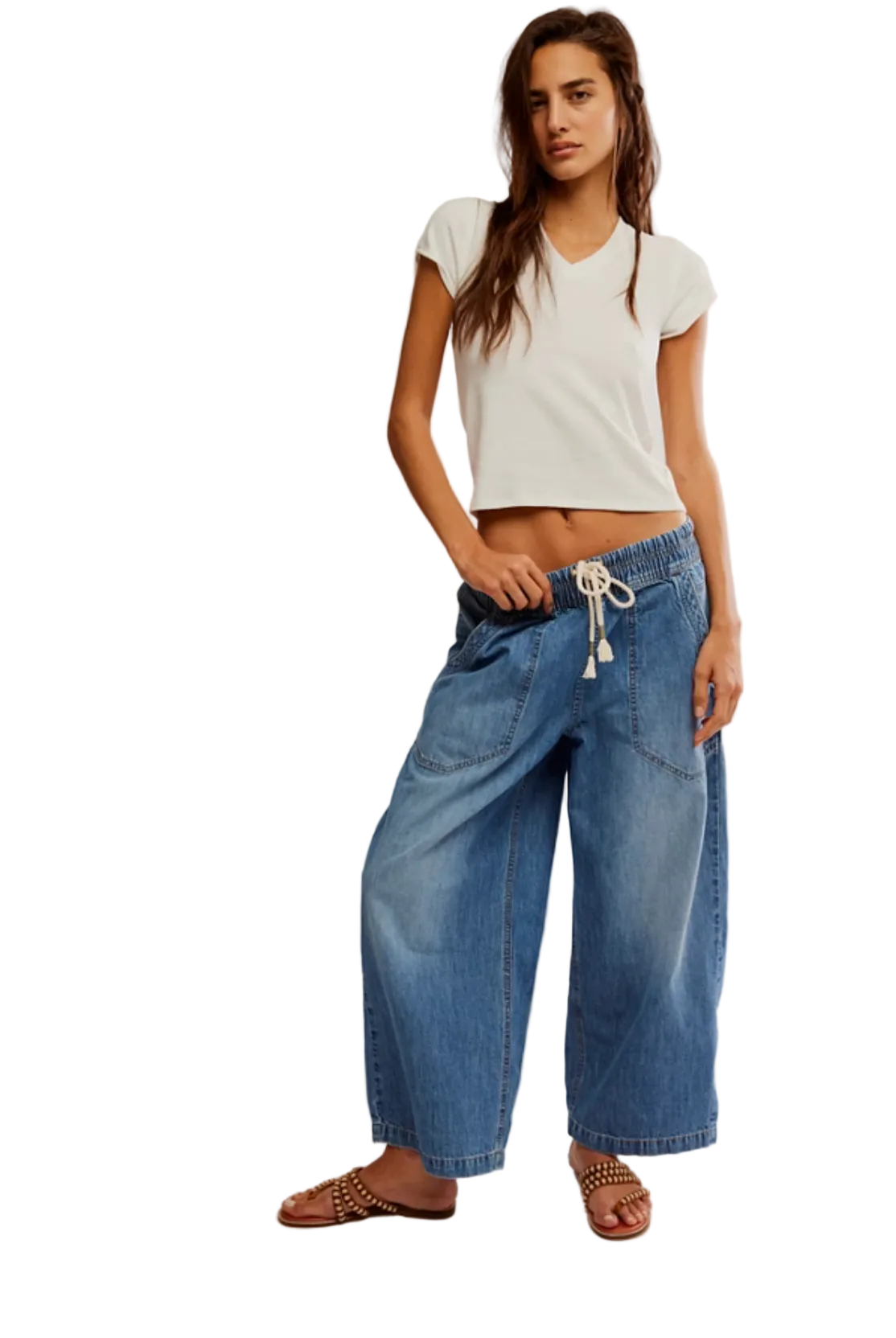 Woman wearing a white top and blue jeans on a plain background