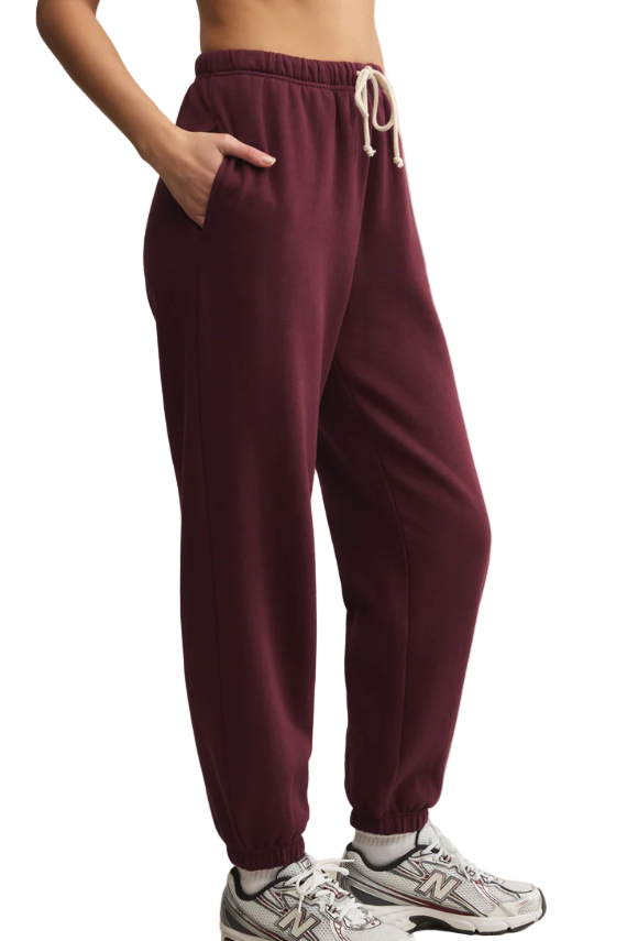 Maroon sweatpants worn by a person on a beige background