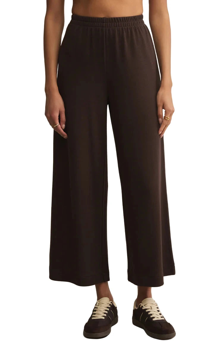 Person wearing black wide-leg pants on a beige background