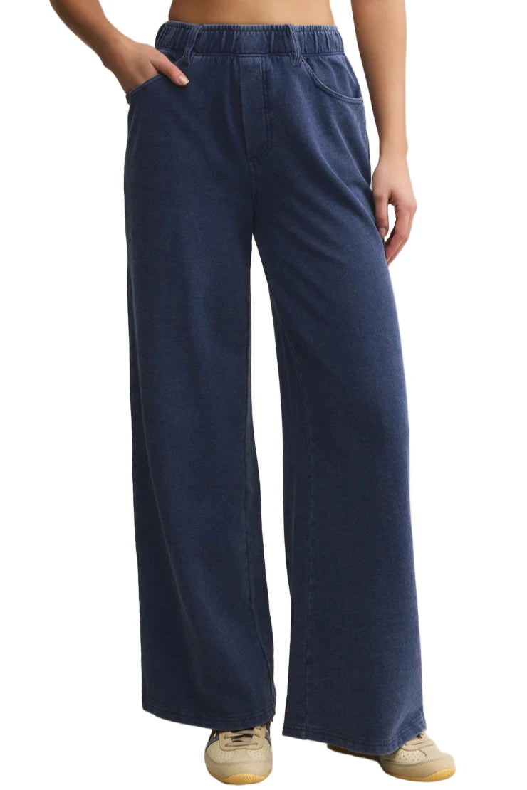 Person wearing blue wide-leg pants on a beige background