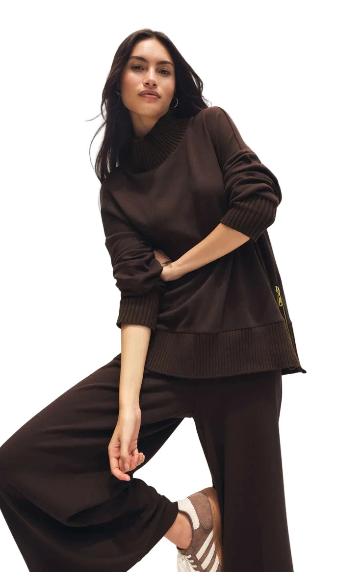 Woman wearing a brown outfit with a logo on a plain background