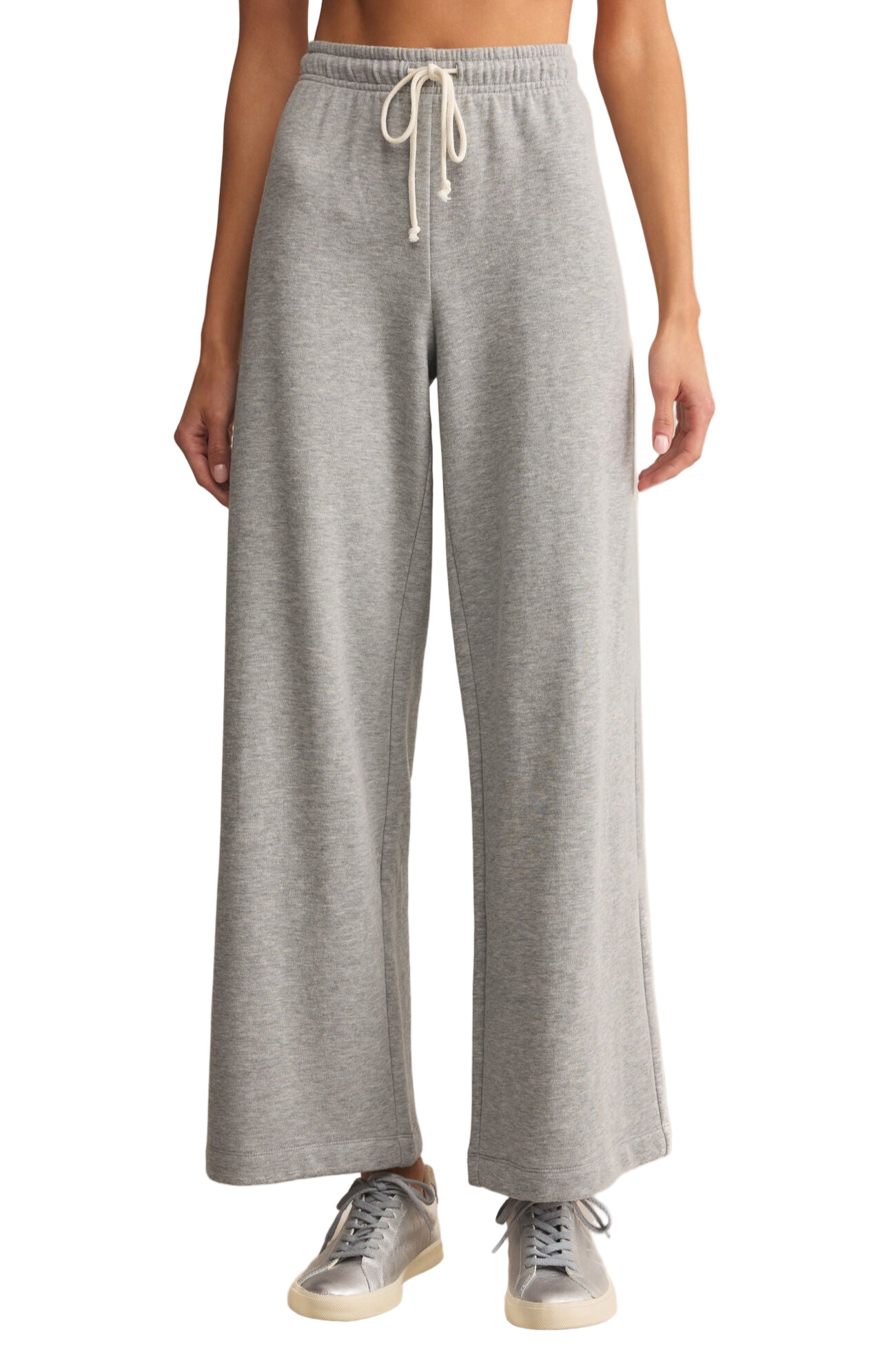 Person wearing gray sweatpants with a beige background